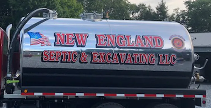 Close view of the polished stainless tank with New England Septic and Excavating LLC hand lettered in red beside a US flag and a military emblem